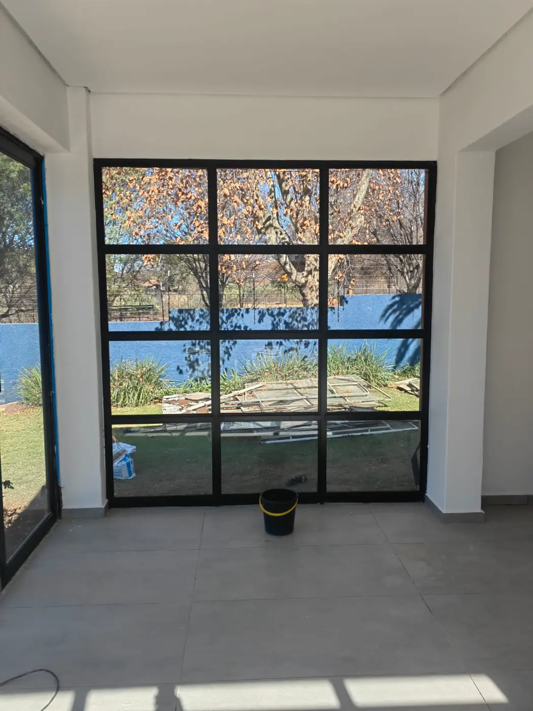 Black steel-framed window wall looking out onto a garden