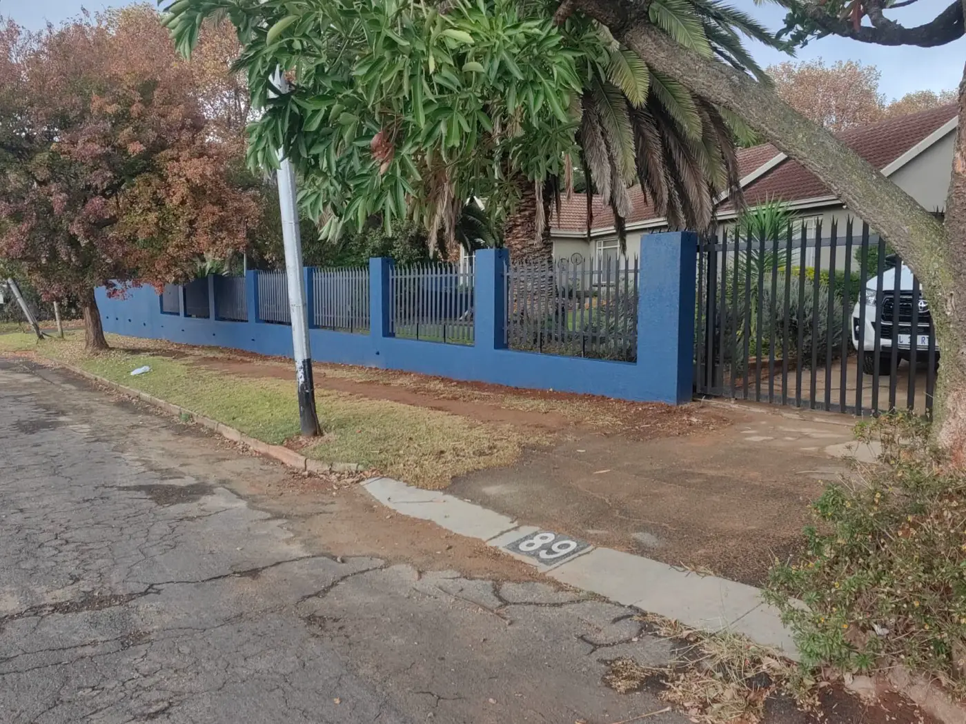 Finished street boundary wall in dark blue with black steel palisade panels